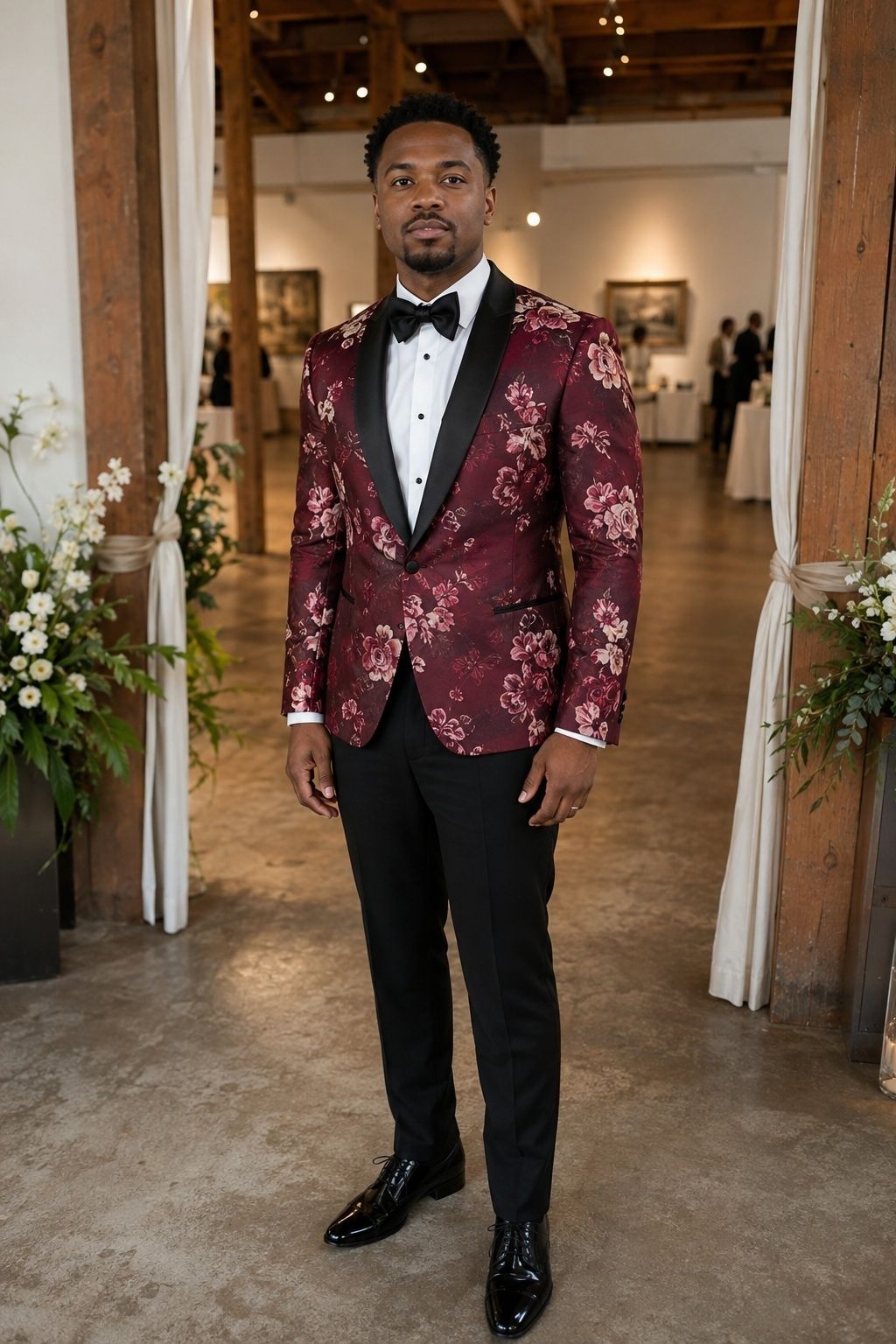 Groom in a burgundy floral tuxedo jacket with black trousers at a gallery wedding.
