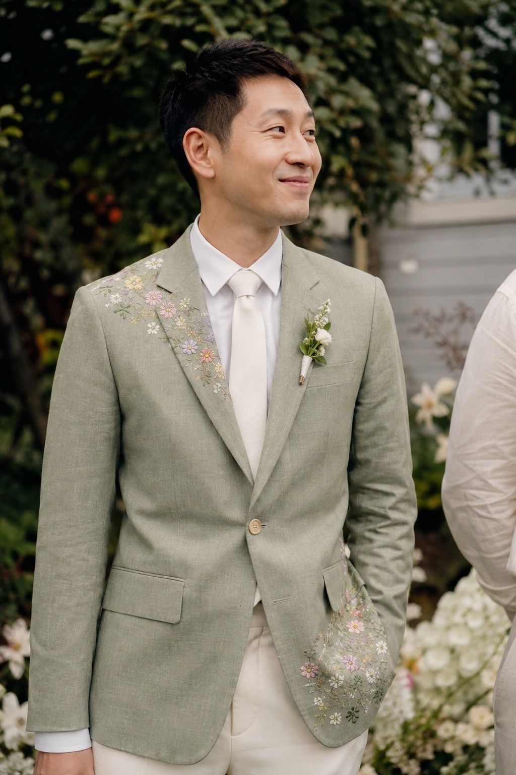 Sage wedding blazer with delicate wildflower embroidery in a garden.