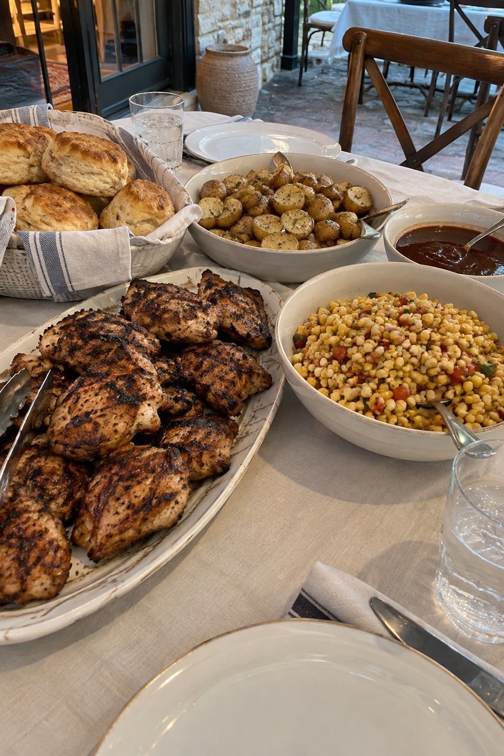 Family-style grilled chicken and summer sides at a wedding dinner