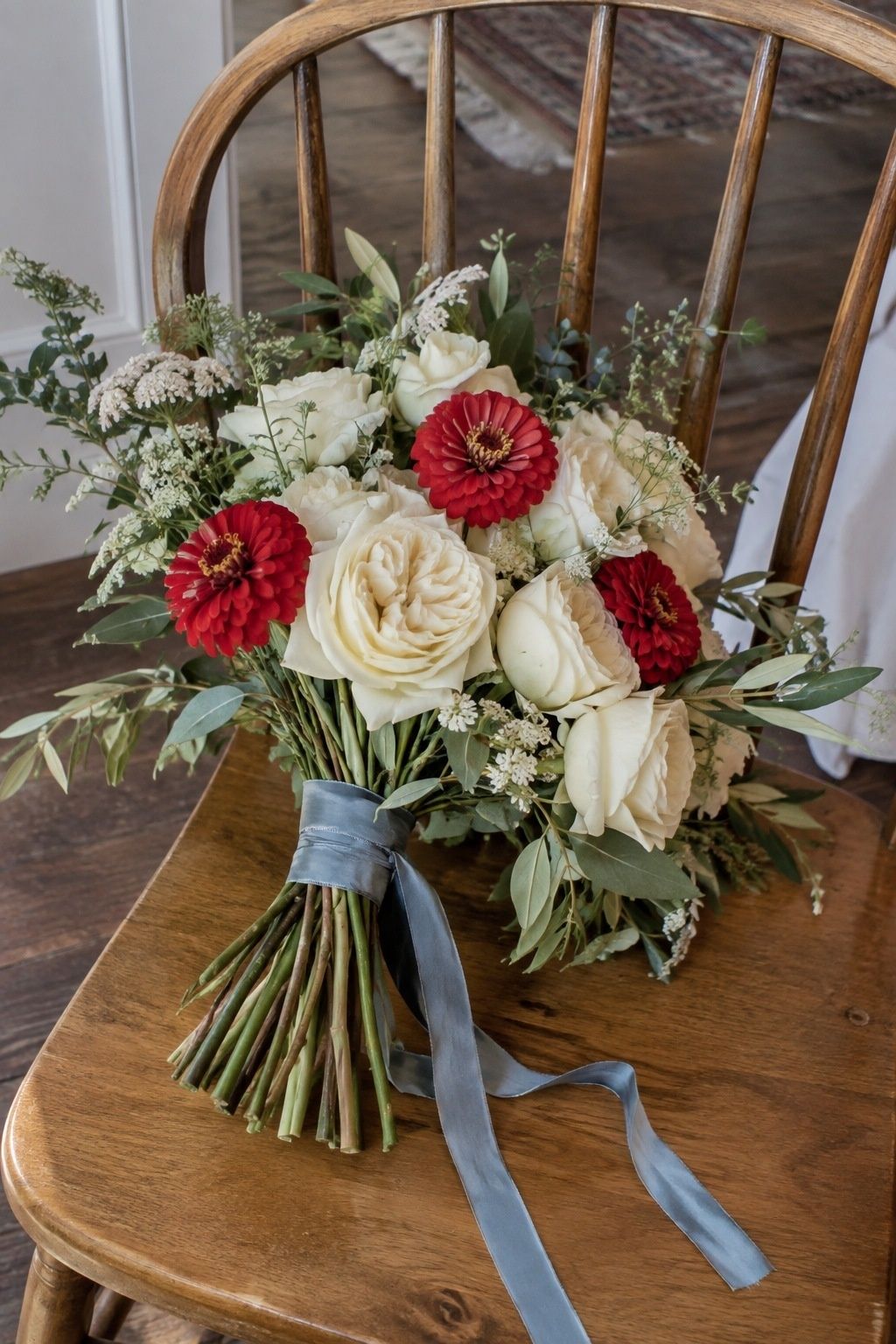 Ivory bridal bouquet with a few red zinnias and blue ribbon