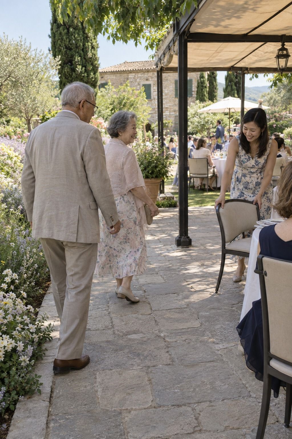 An older couple follows firm terrace paving to nearby shaded seating while a relative pulls out a chair.
