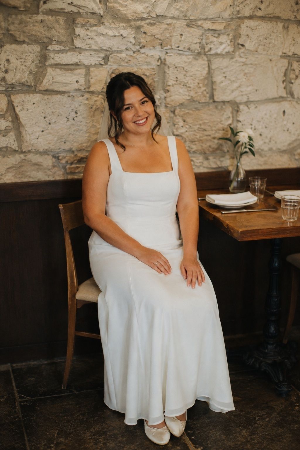Bride seated comfortably in a lightweight wedding dress at an intimate restaurant table