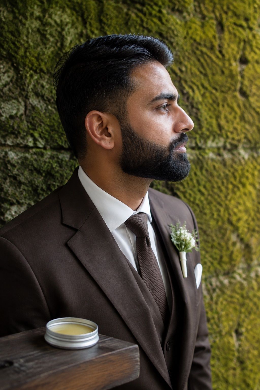 Profile of a groom with a neatly shaped beard and natural hair texture.