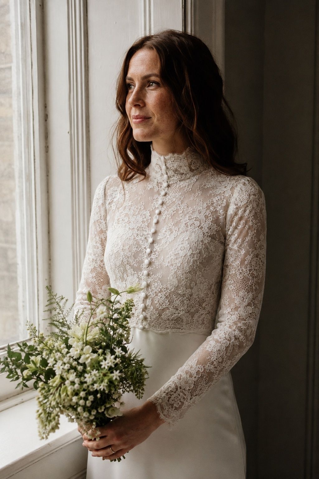 Close upper-body portrait of adult freckled bride with chestnut hair wearing restrained Victorian-inspired fine lace standing collar
