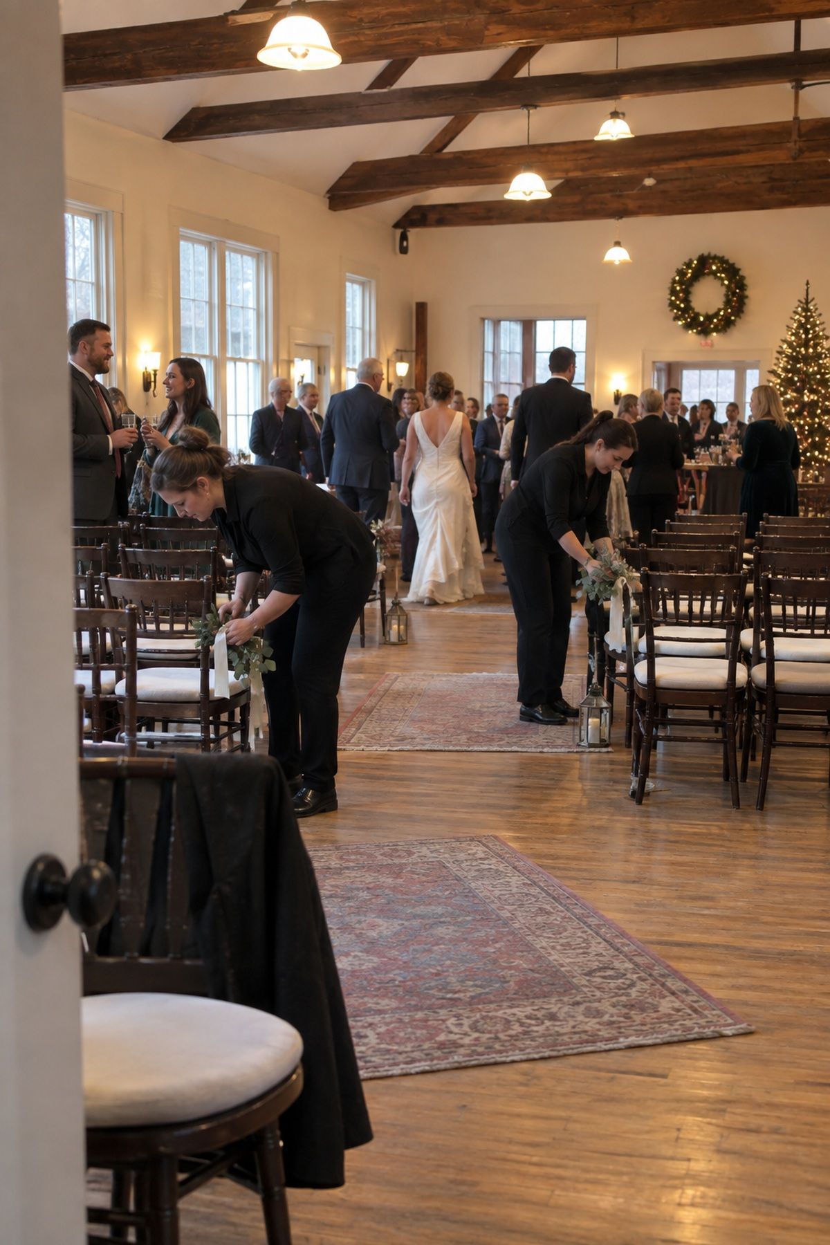 Wedding helpers reset ceremony chairs as guests move to cocktail hour in the same hall.