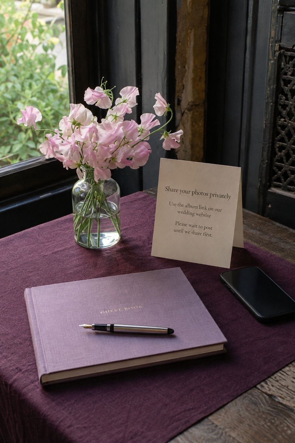 Private photo sharing reminder beside a wedding guest book and pink flowers