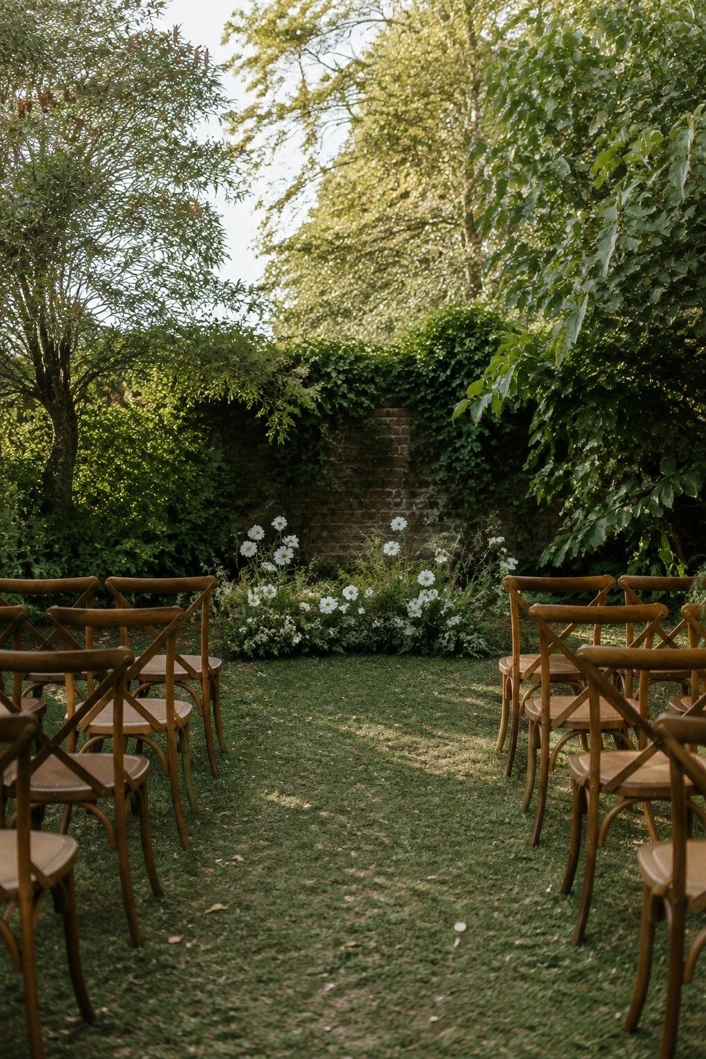 Short garden wedding aisle with wooden chairs and white flowers