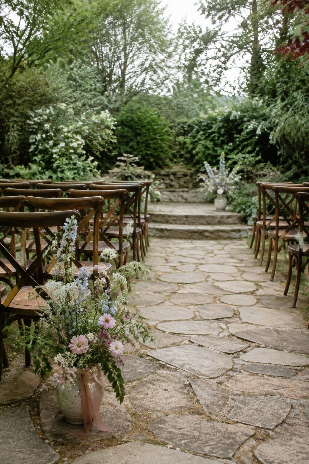 Intimate garden wedding aisle with one wildflower entrance arrangement and one modest altar arrangement
