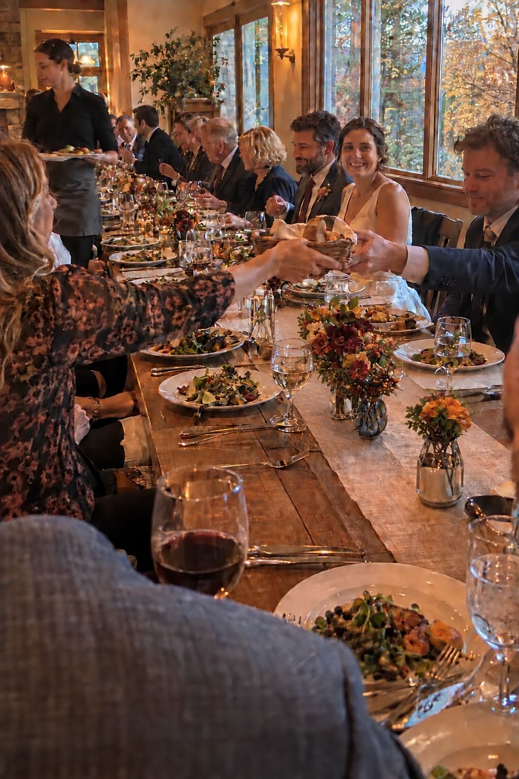 One active long-table dinner keeps the newlyweds among about twenty guests while bread is passed and service aisles stay open.