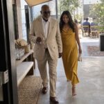 Two arriving guests immediately find a shaded awning, chilled water, hand fans, a bench and a visible route to the ceremony.