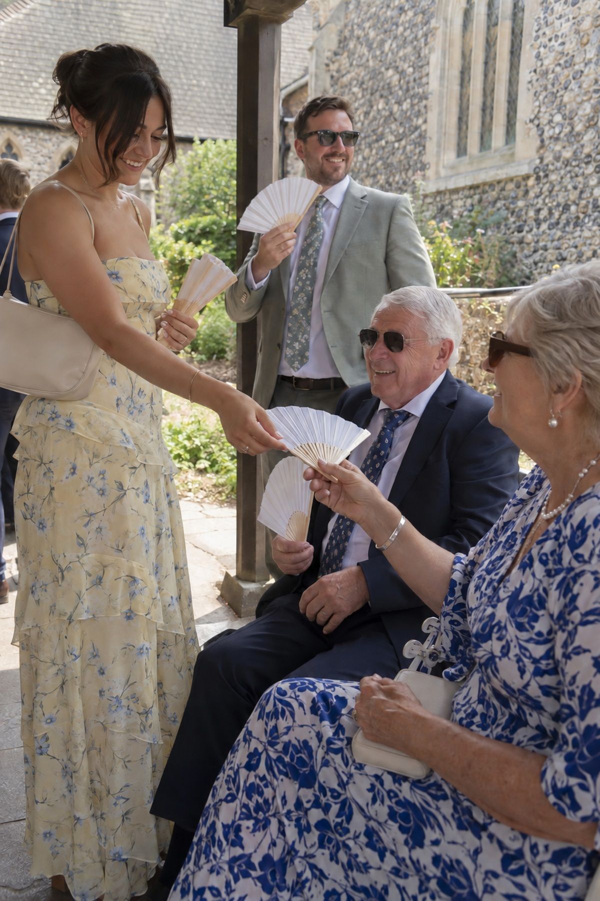 Guests use paper fans while arriving for a warm July wedding ceremony.