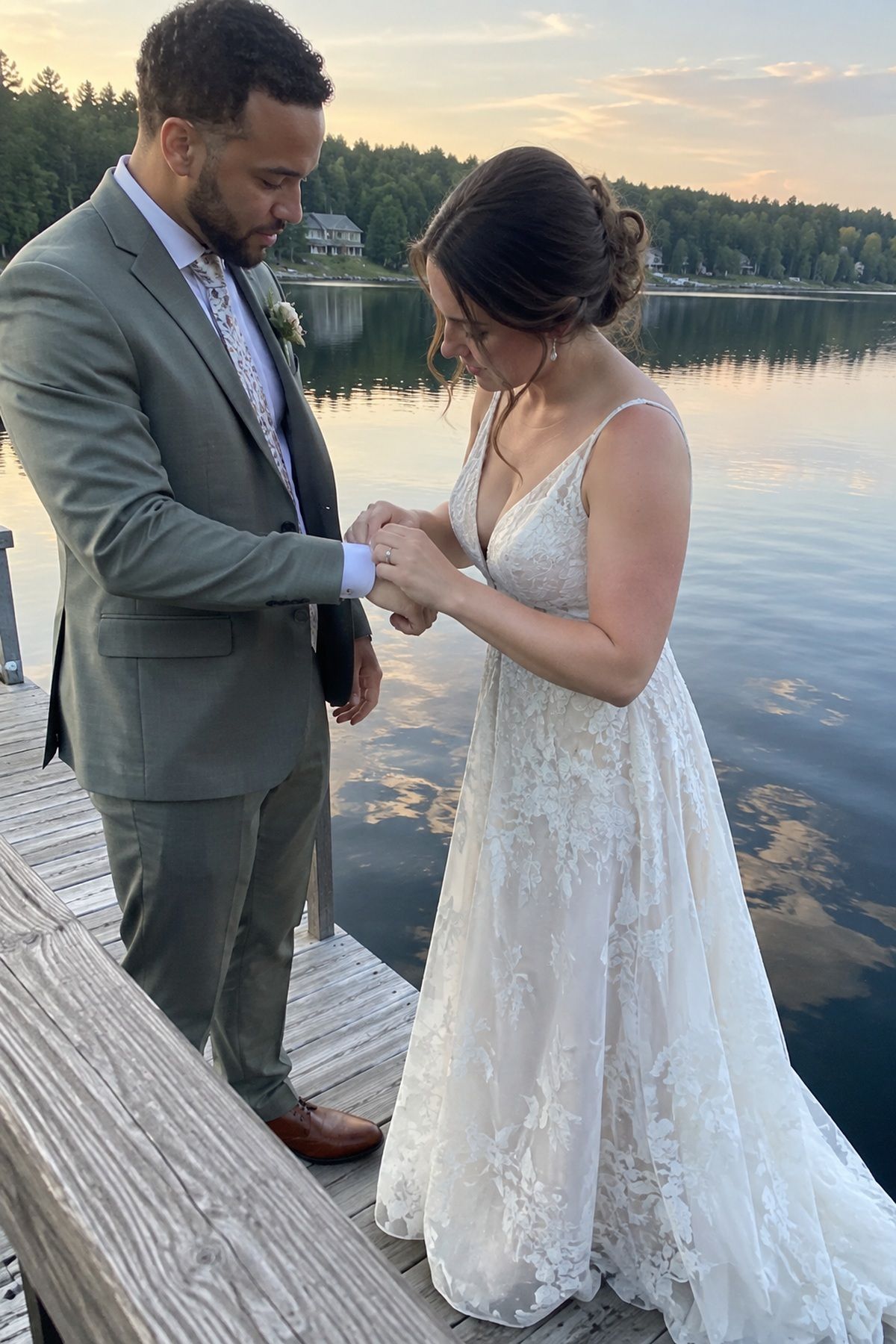 A couple pauses beside calm lake reflections on a July wedding dock.