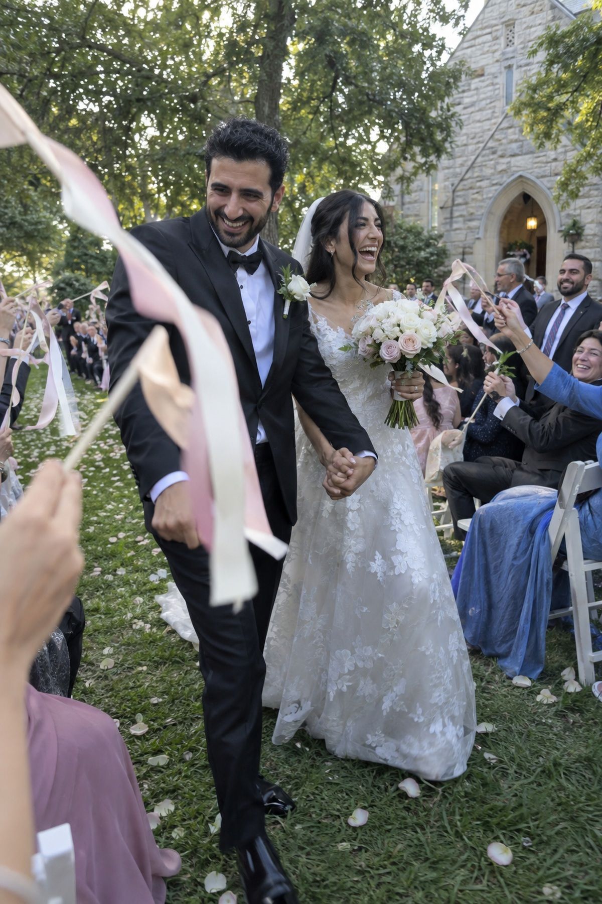 Guests wave ribbon wands as a newlywed couple exits a July wedding ceremony.