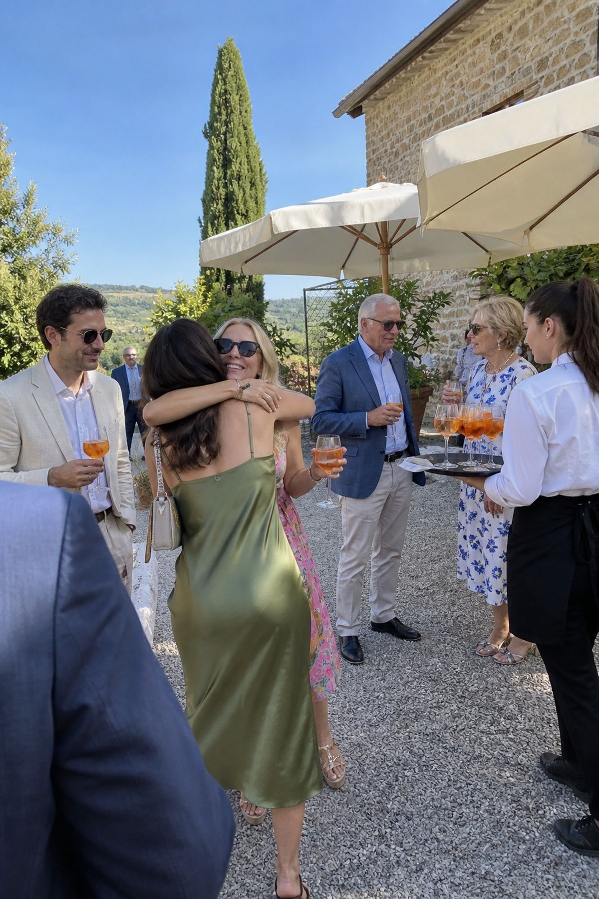 Wedding guests mingle beneath market umbrellas during a shaded July cocktail hour.