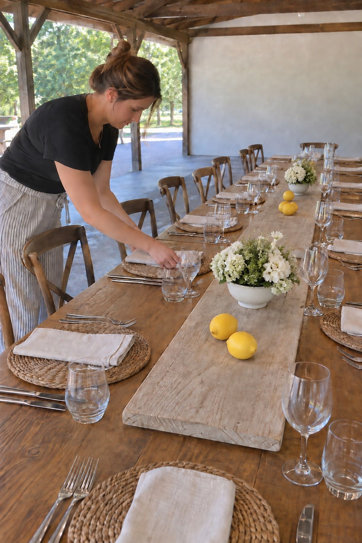 A coordinator finishes July wedding table details before guests sit down.