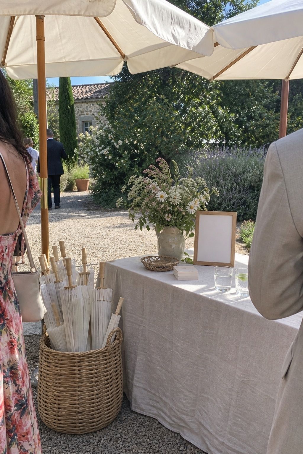 Shaded outdoor wedding welcome table with market umbrellas and parasols where guests wait
