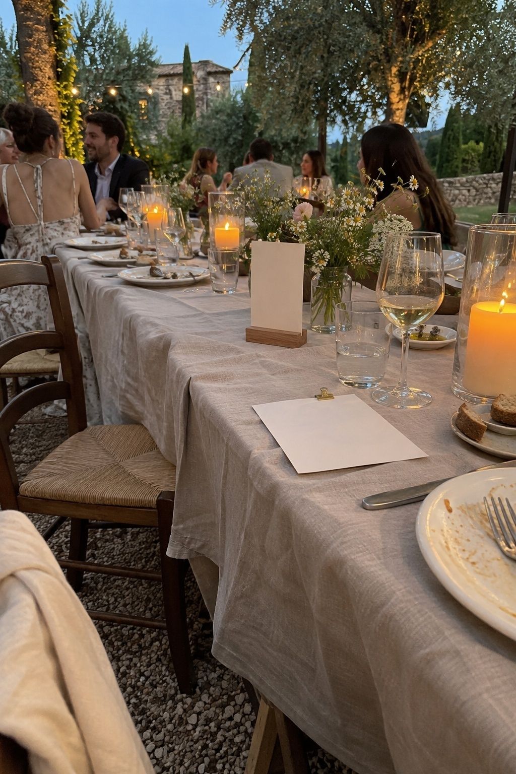 Wind-safe outdoor wedding table with clipped linen, weighted card and hurricane candles