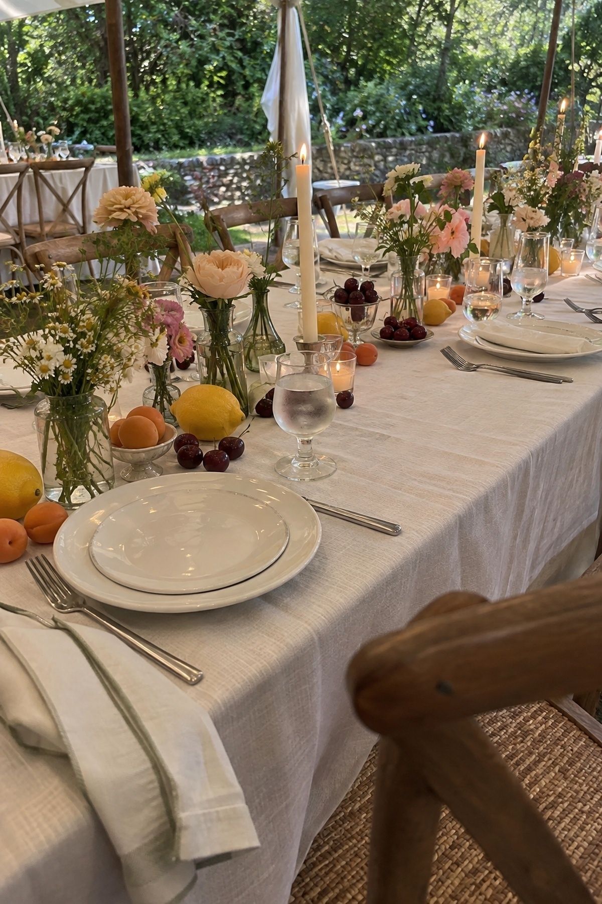 June wedding fruit and floral tablescape with lemons, apricots, cherries, bud vases, and pale linen.