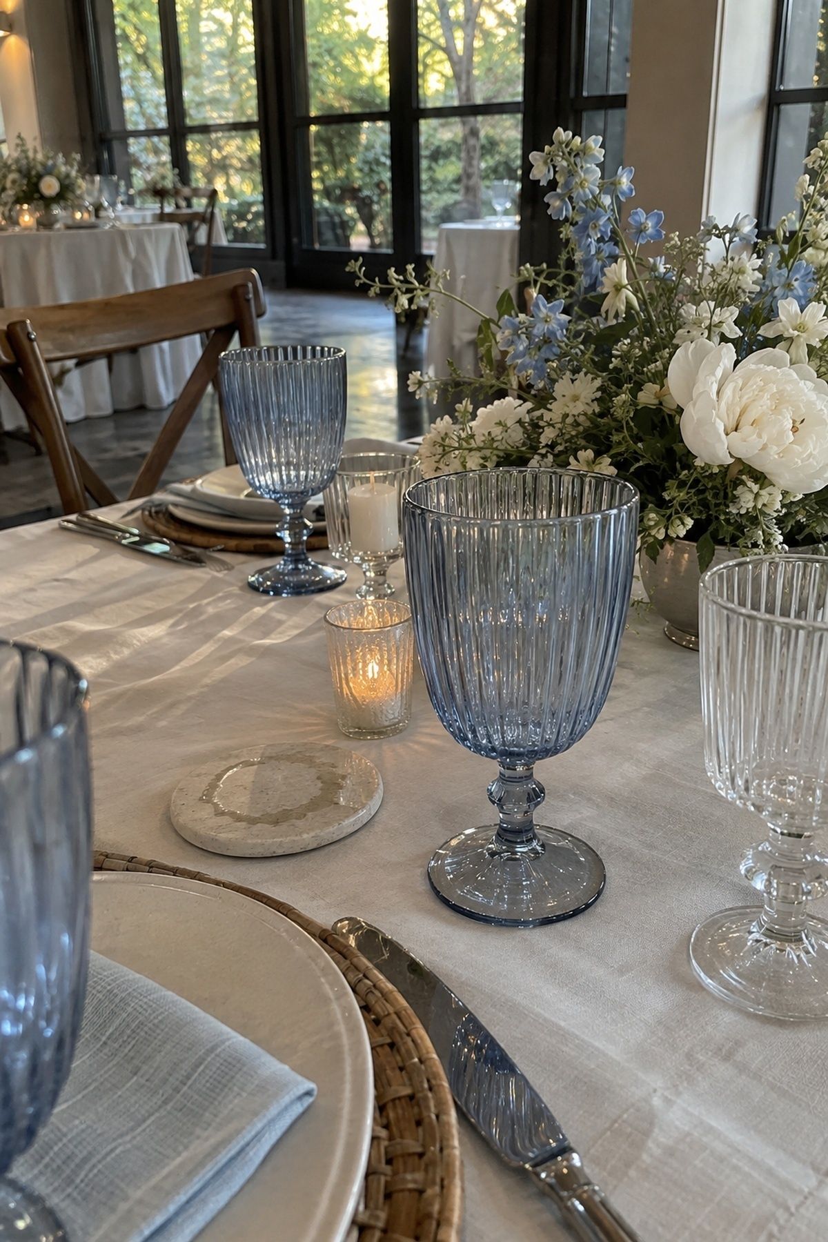 Pale blue ribbed goblets with white and blue garden flowers at a June wedding reception.