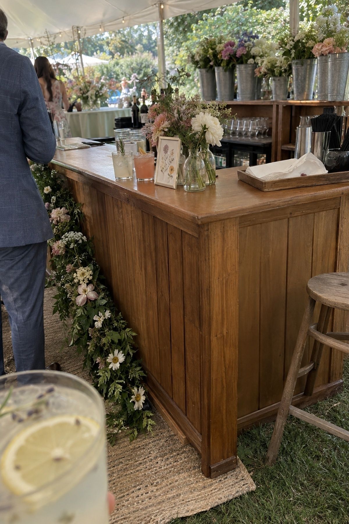 Floral June wedding bar with seasonal stems, a modest garland, and signature drinks.