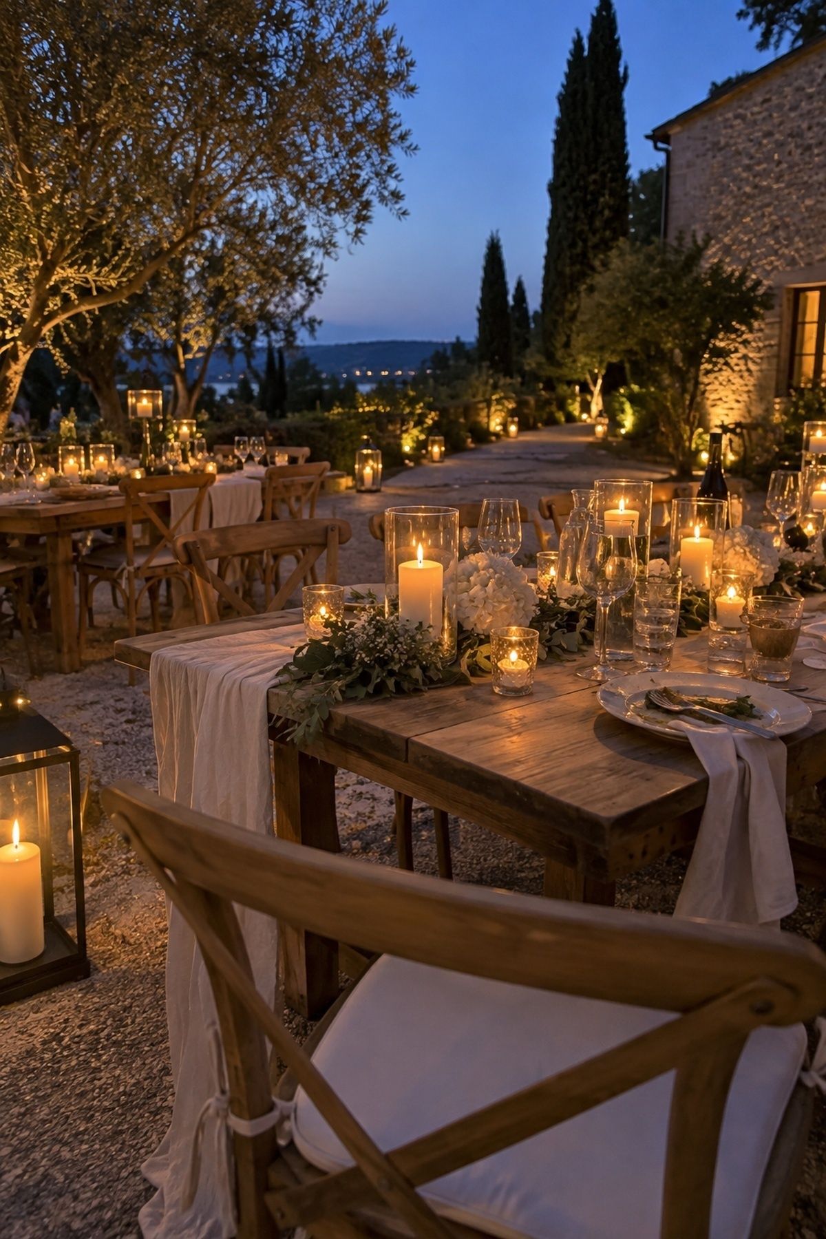 Glass hurricane candles and lanterns glowing at a small June wedding after sunset.