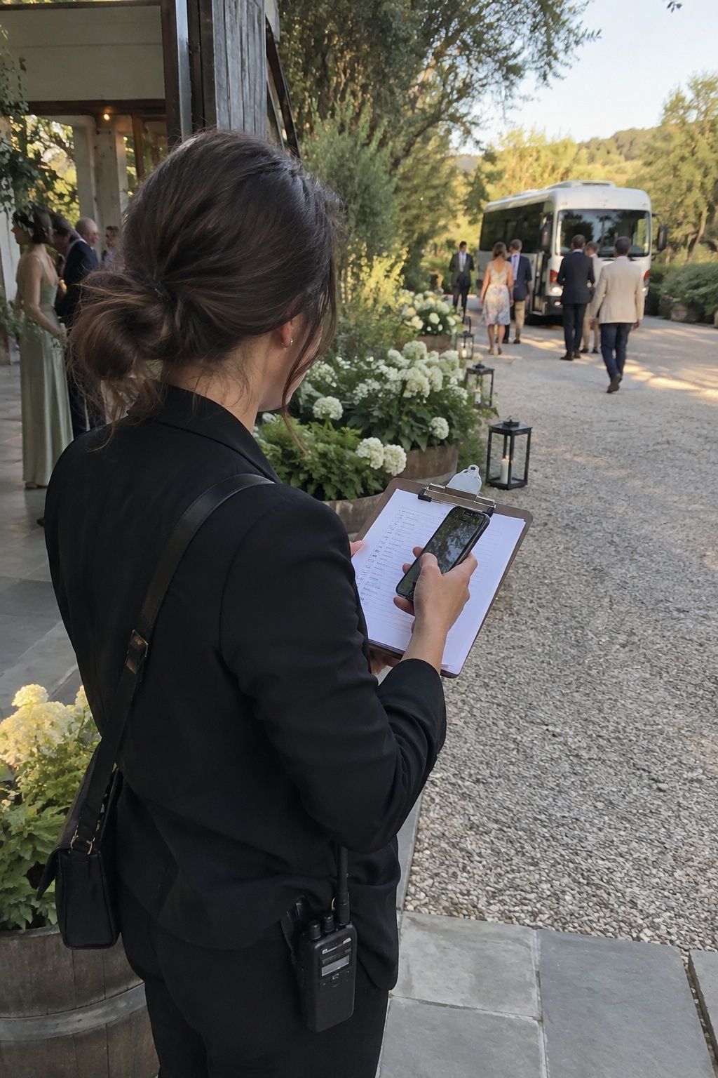 Wedding coordinator checking a phone and arrival list beside guest transport for a Labor Day wedding