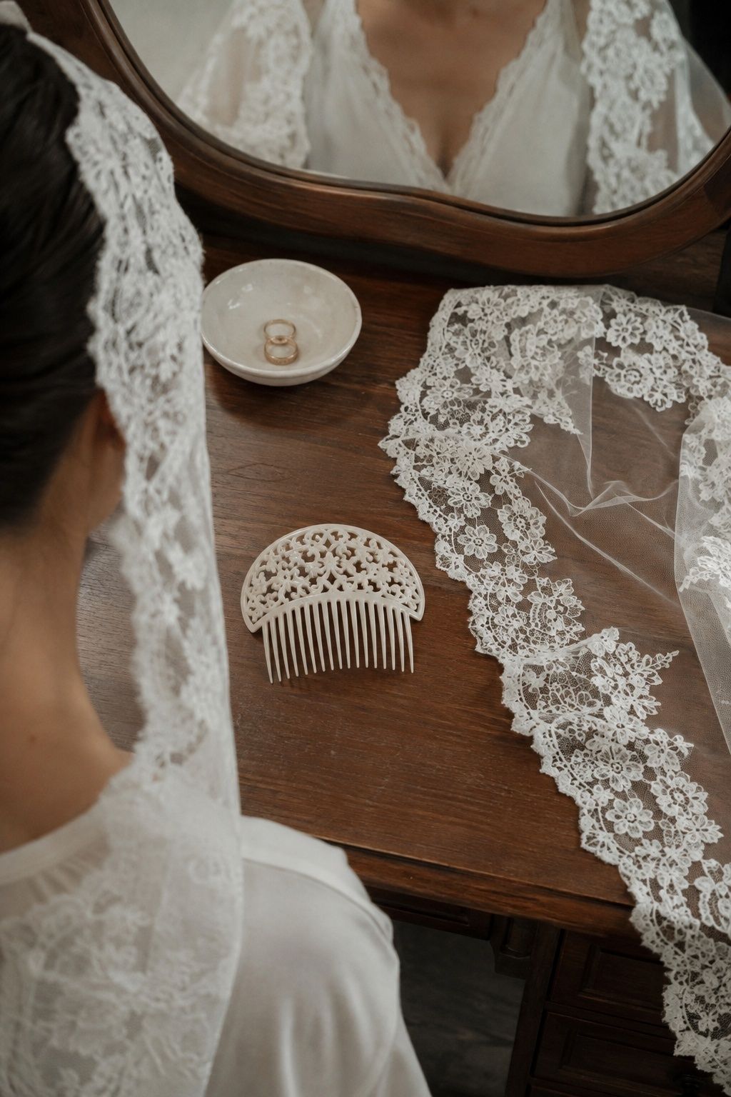 Low ivory bridal comb beside a lace mantilla on a dressing table