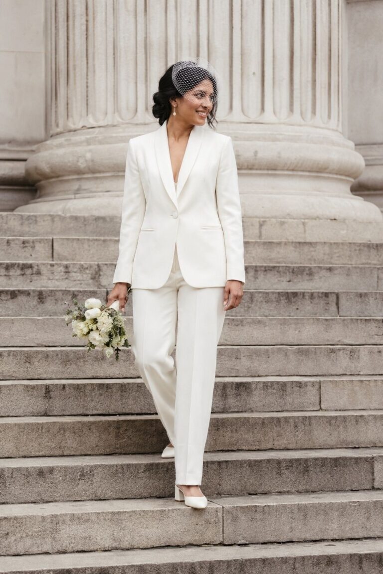 Bride in an ivory trouser suit and low heels on pale stone steps
