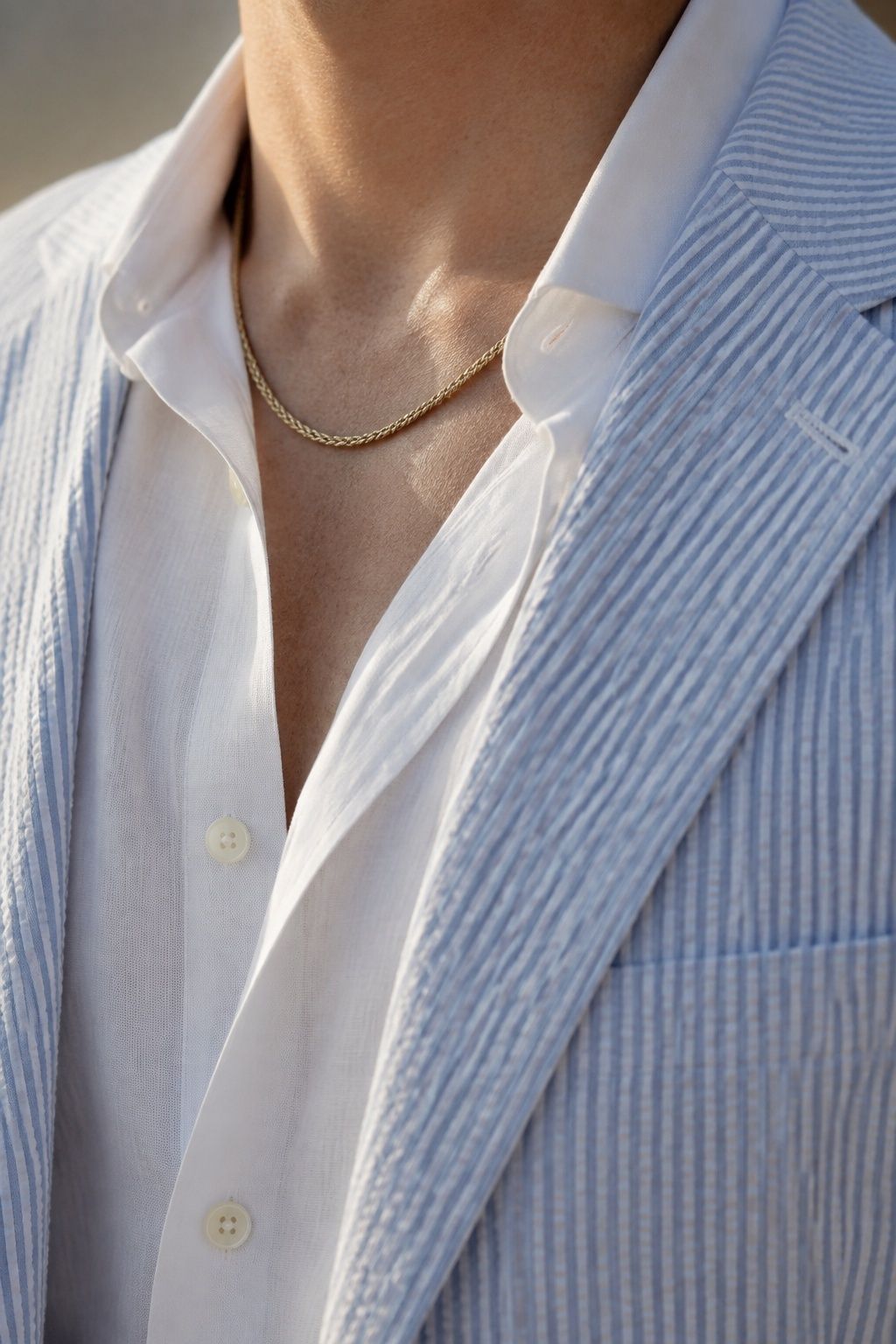 A modest twisted gold rope chain and textured blue seersucker summer wedding suit