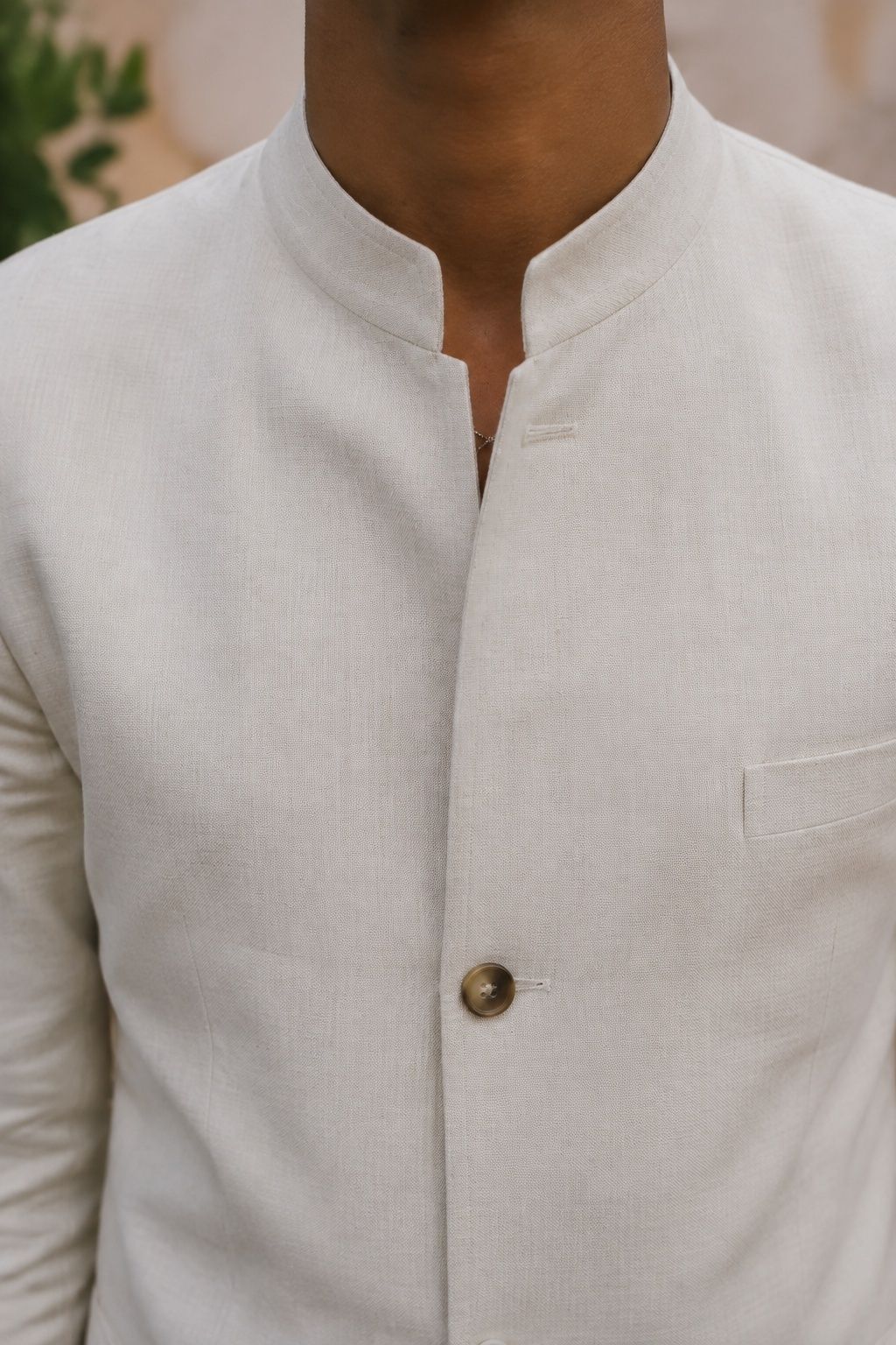 Subtle chain tucked into a mandarin-collar wedding jacket, just a glimpse at the neck opening
