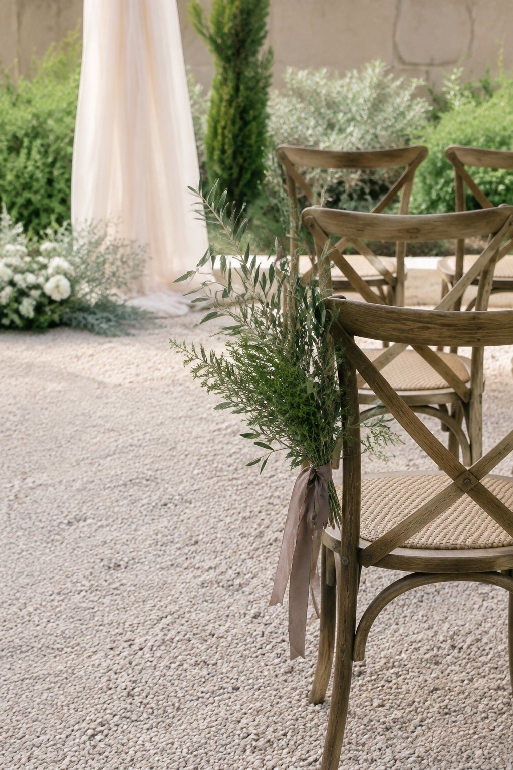 Olive and sage foliage tied with mocha ribbon to a wooden ceremony chair.