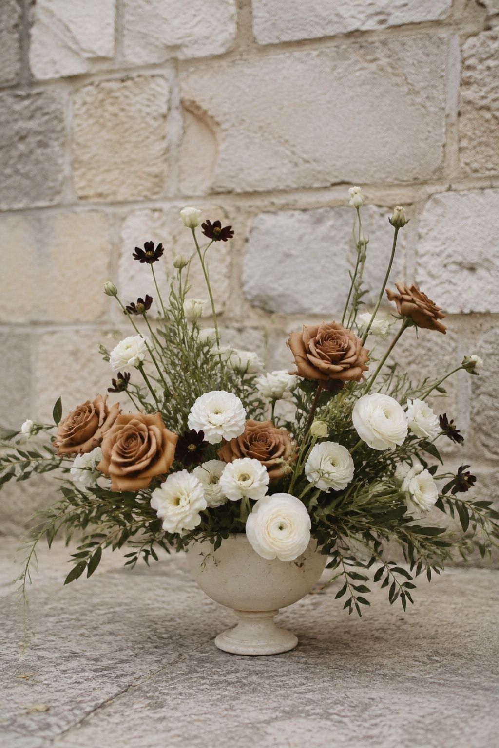 Airy arrangement of toffee roses, cream blooms and chocolate cosmos in a pedestal bowl.