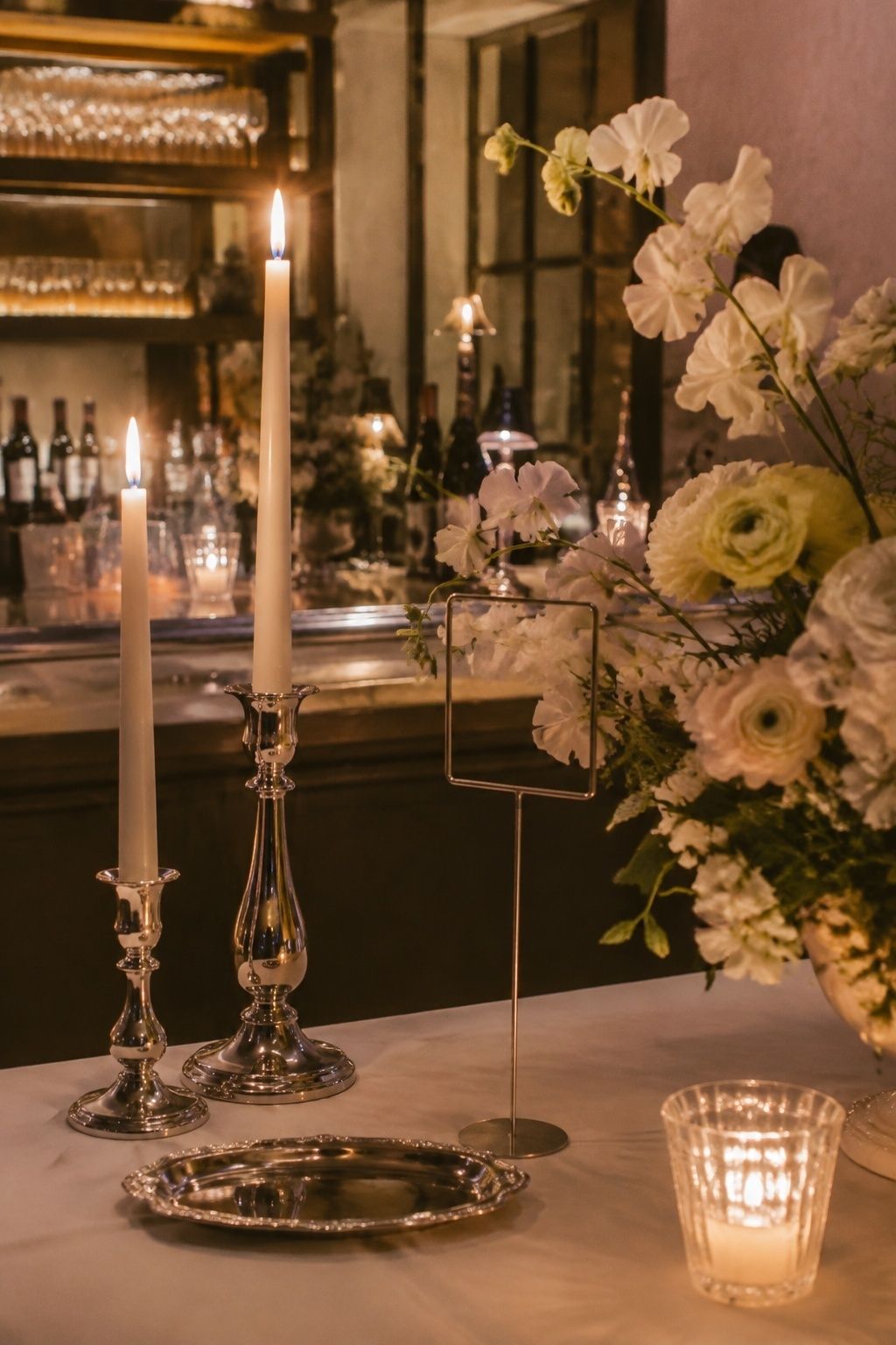 Small chrome and silver accents warm an intimate evening wedding bar.