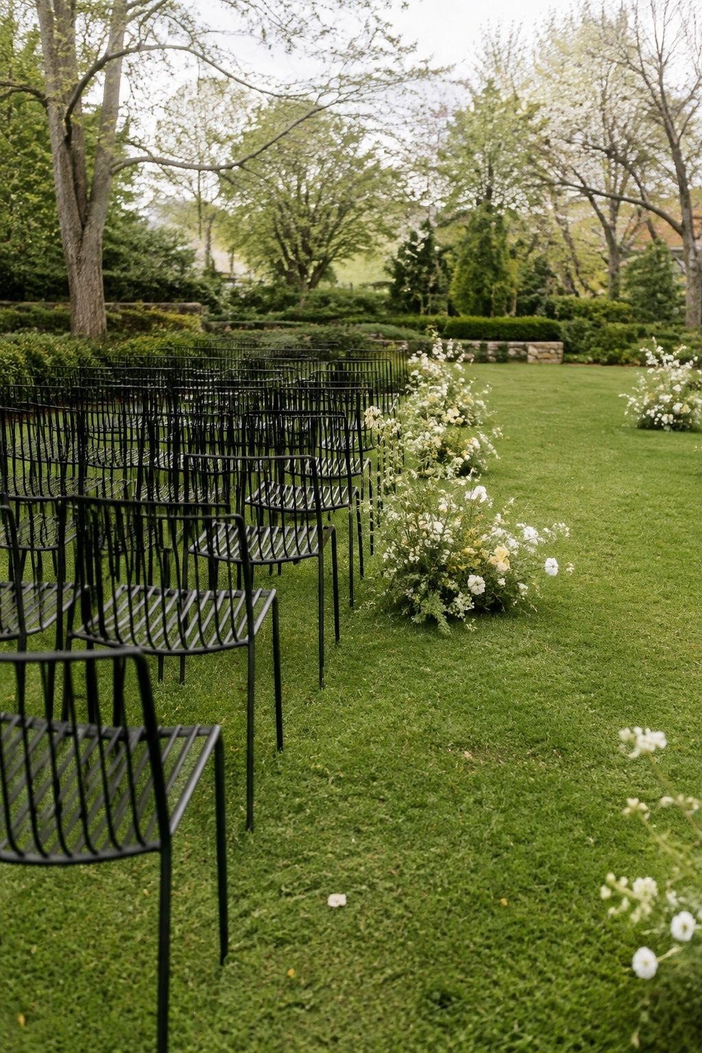 Slim black chairs sharpen a relaxed spring garden wedding ceremony.