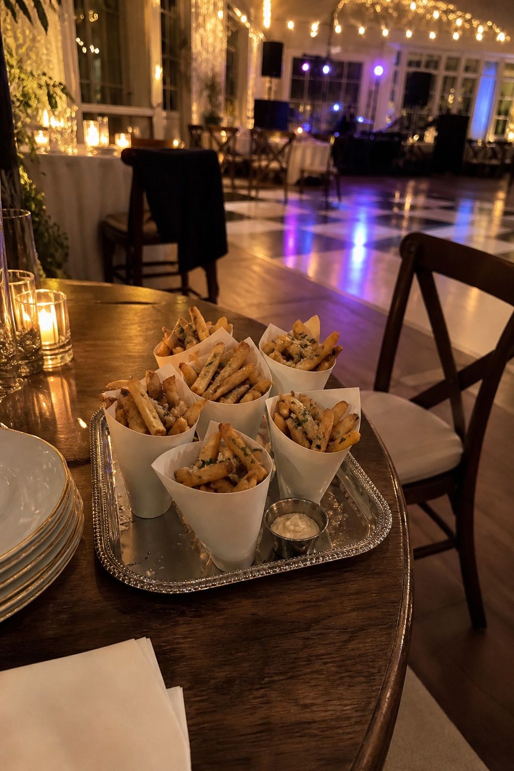 A small hand-carry tray of warm fries in paper cones pauses beside the dance-floor edge