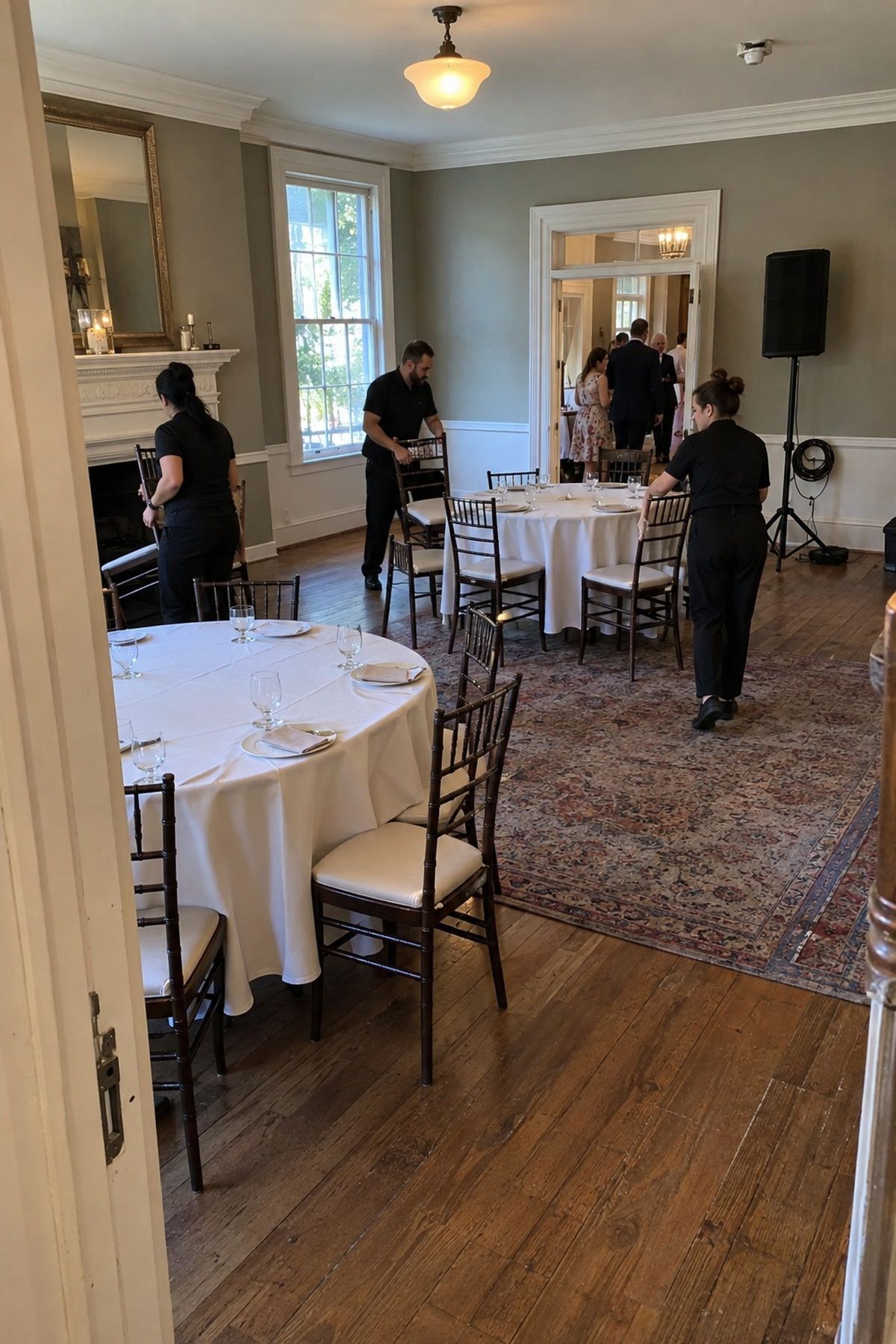 Venue staff turn a ceremony room into dinner while keeping the speaker and service lane clear.