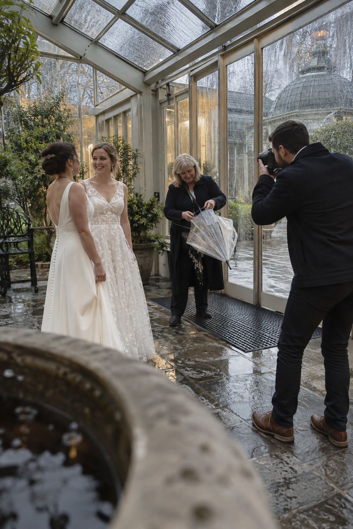 Two brides use a covered conservatory entry for November rain portraits.