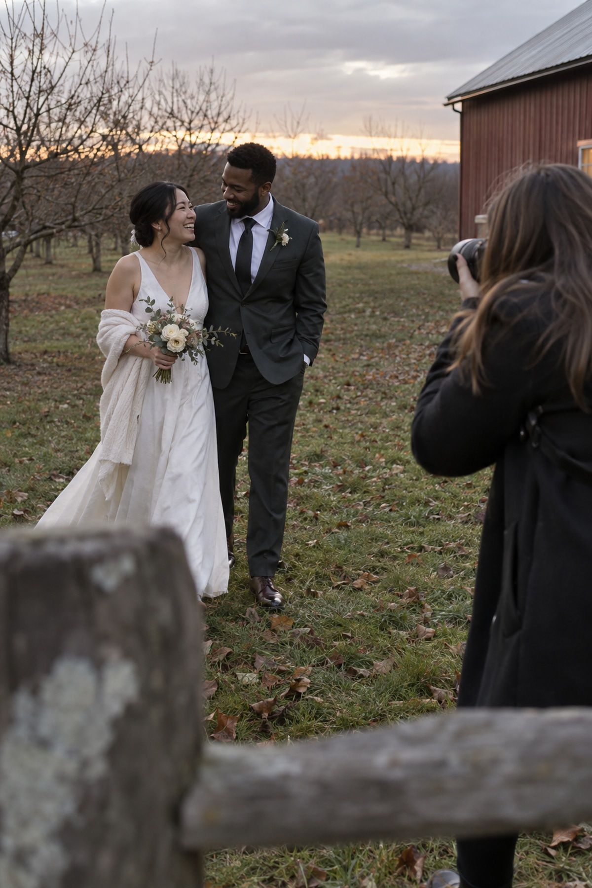 A newlywed couple walks through the last November daylight near their reception.