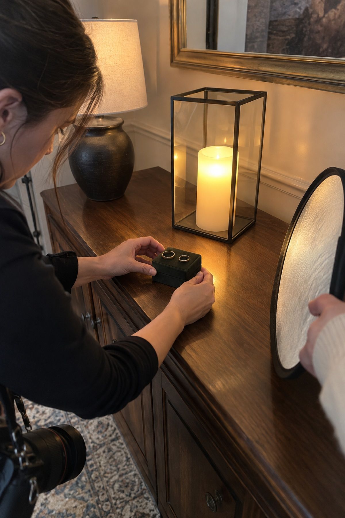 A photographer arranges two wedding bands beside safe warm LED light.