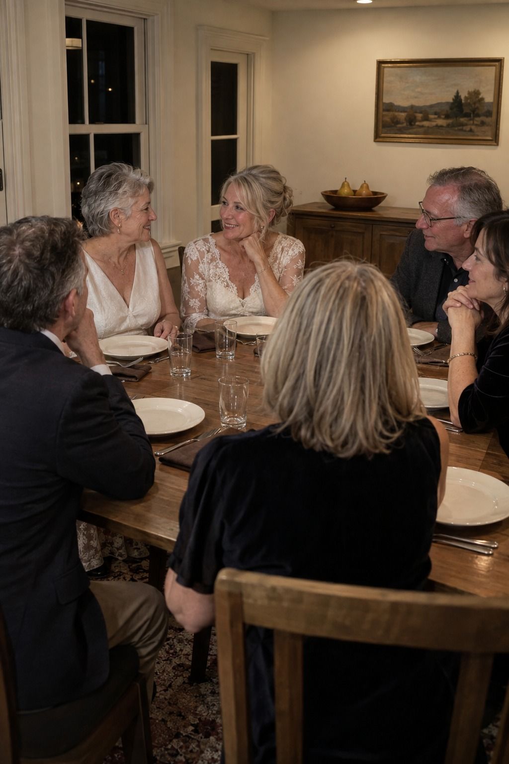 Two older brides and relatives talk between courses at an unthemed table with clean empty plates while exactly three distant pears provide the only seasonal note.