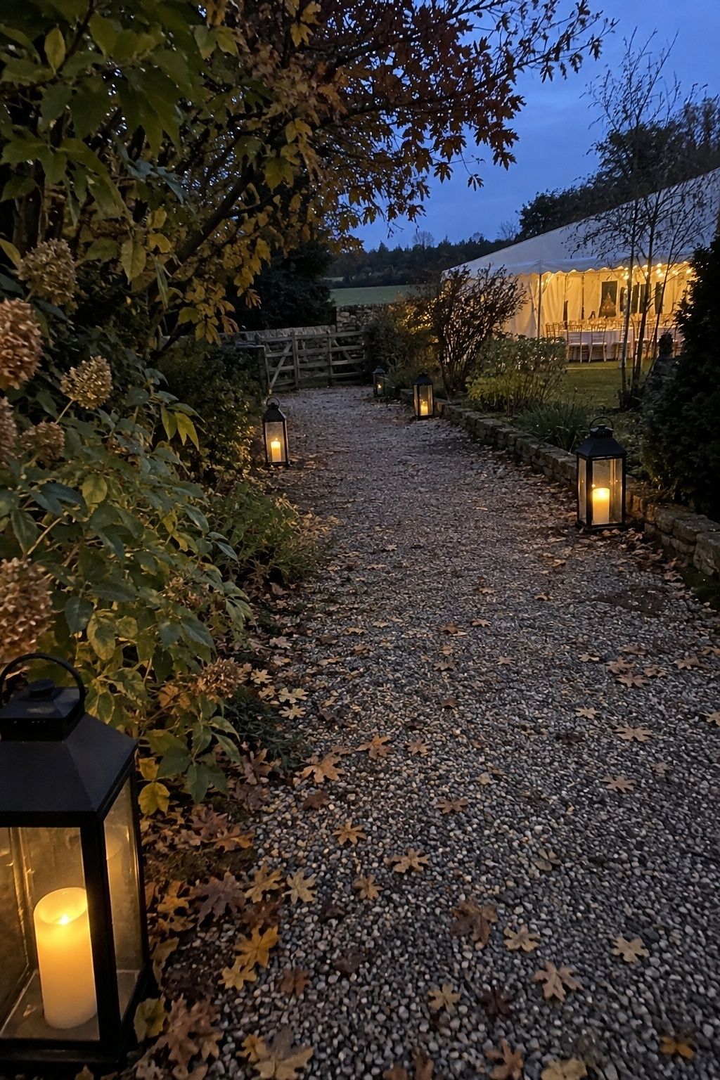 Safe lanterns lining a gravel path to an October wedding reception after sunset