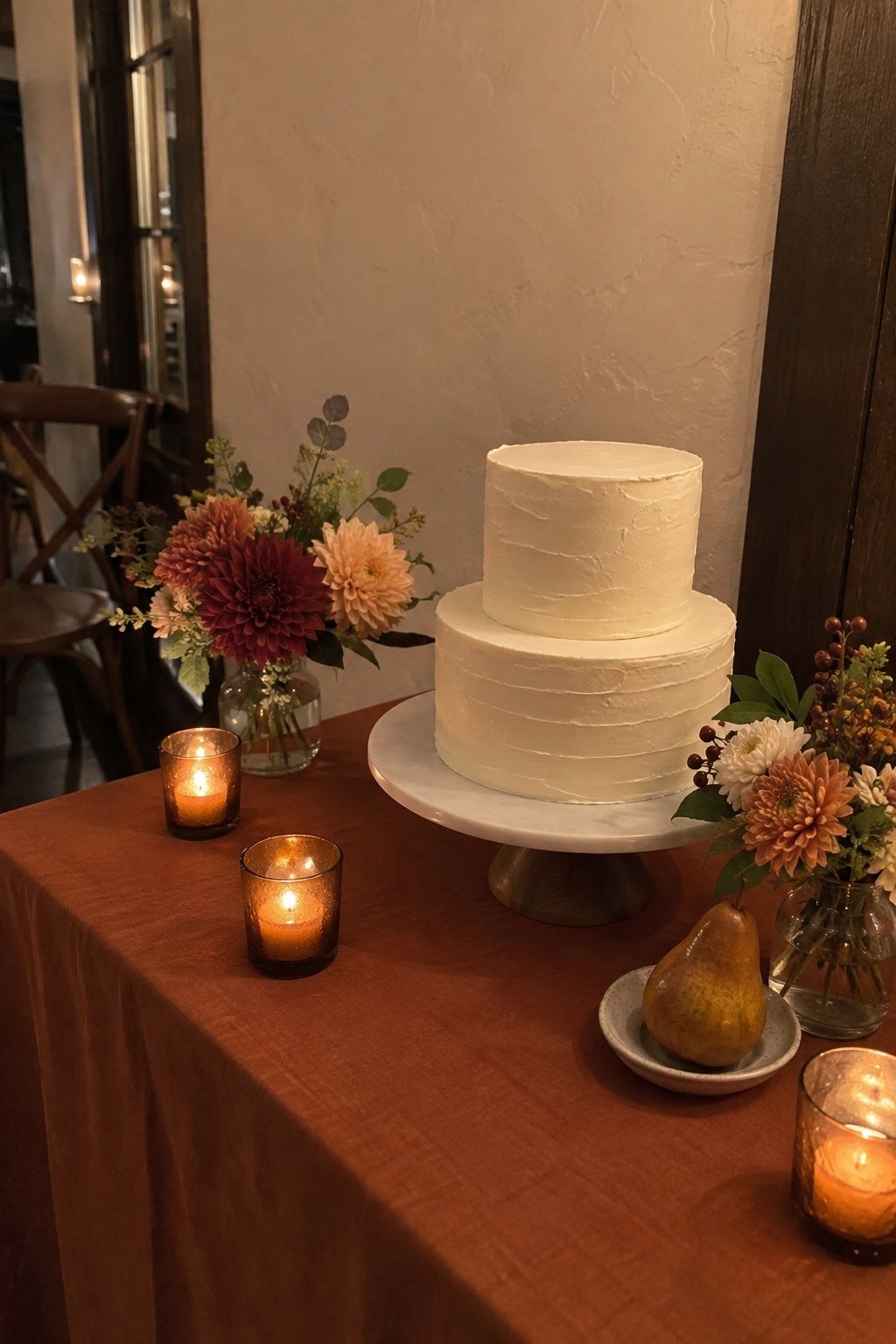 Candlelit October wedding cake table with seasonal flowers kept off the cake