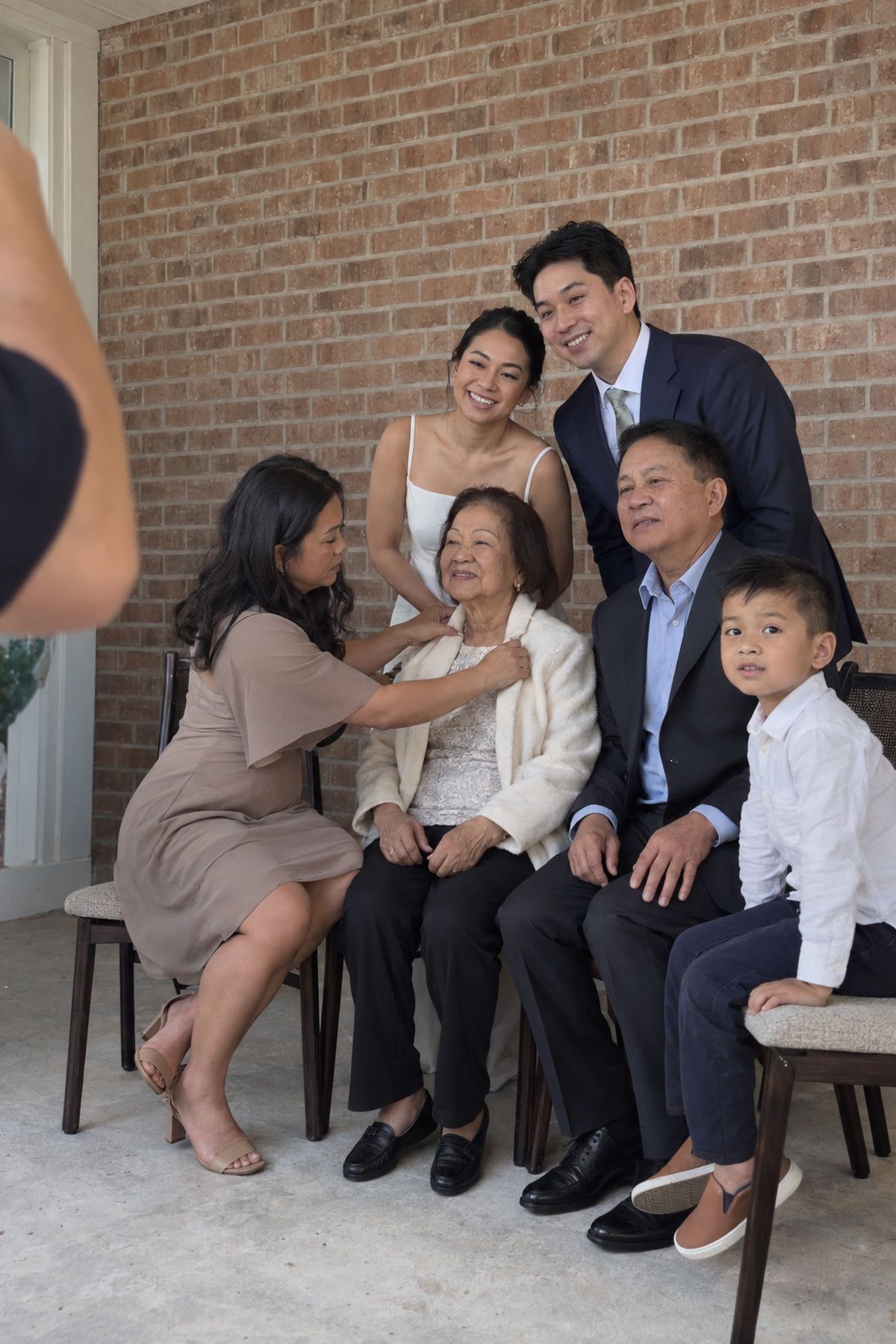 A multigenerational family settles into a seated October wedding portrait.