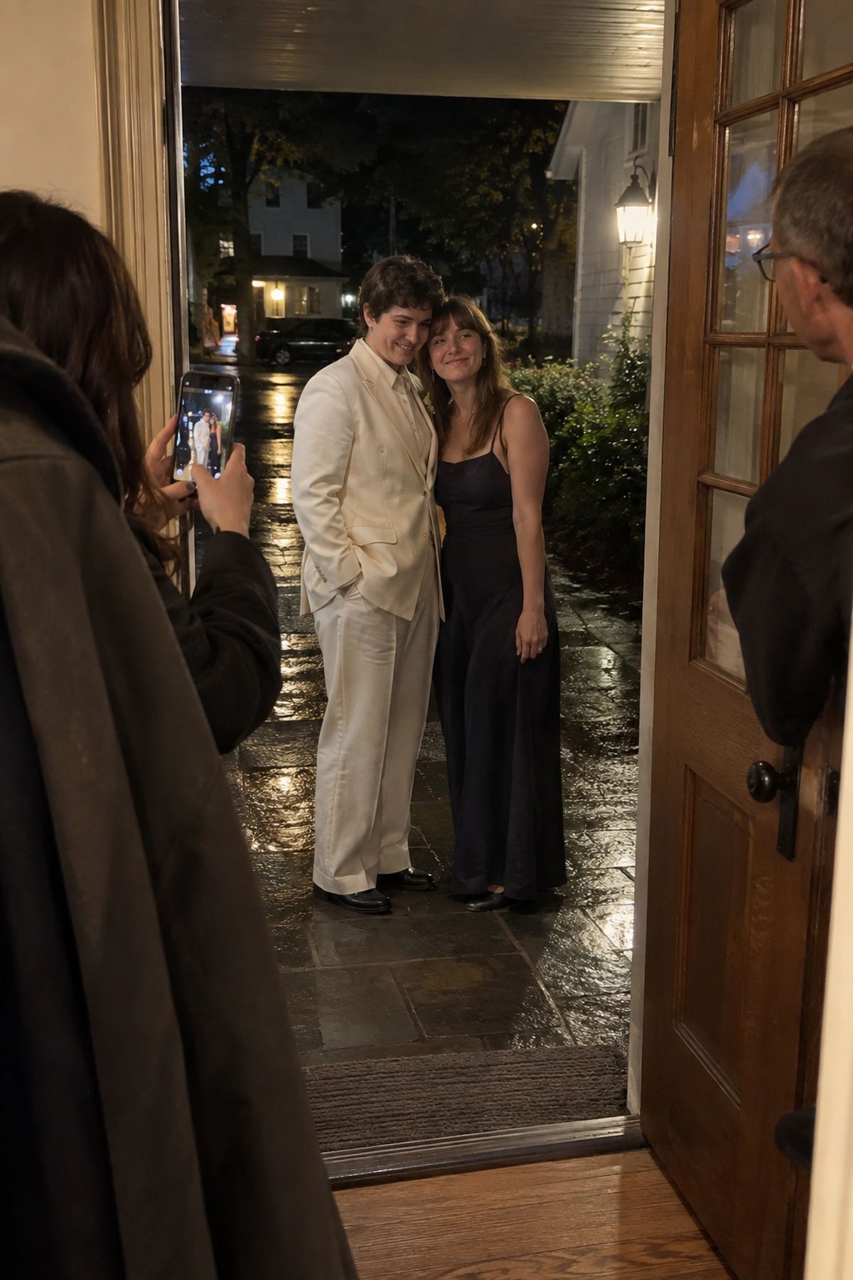Newlyweds pause in a rainy doorway for a final October wedding night portrait.