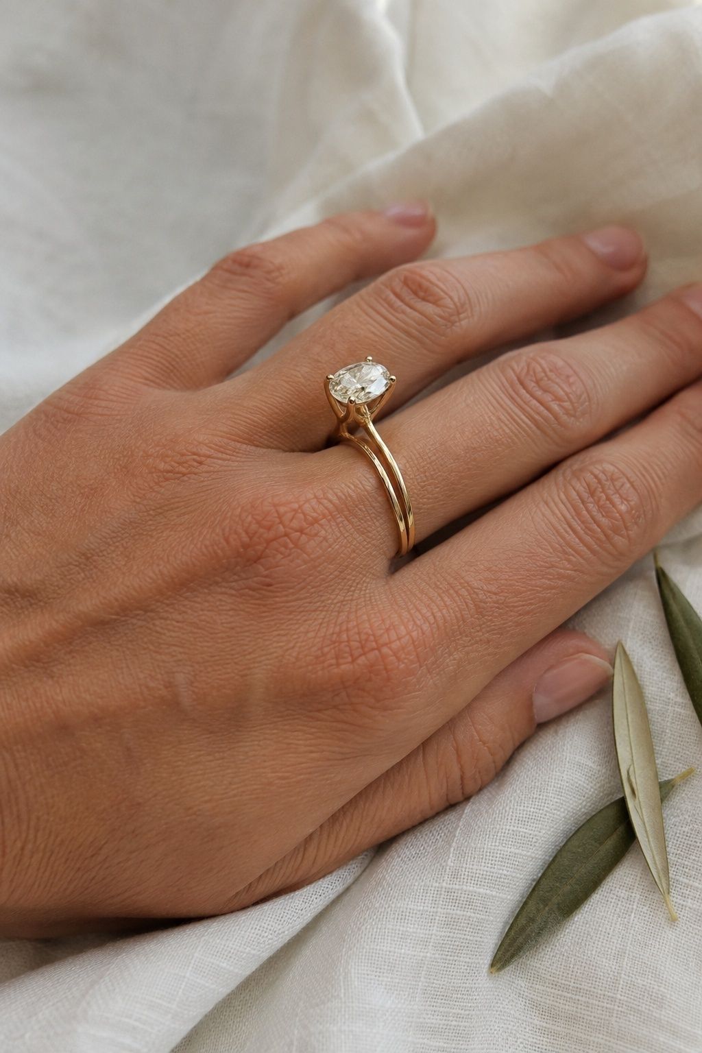 Side view of an oval engagement ring basket clearing a straight gold wedding band on a hand