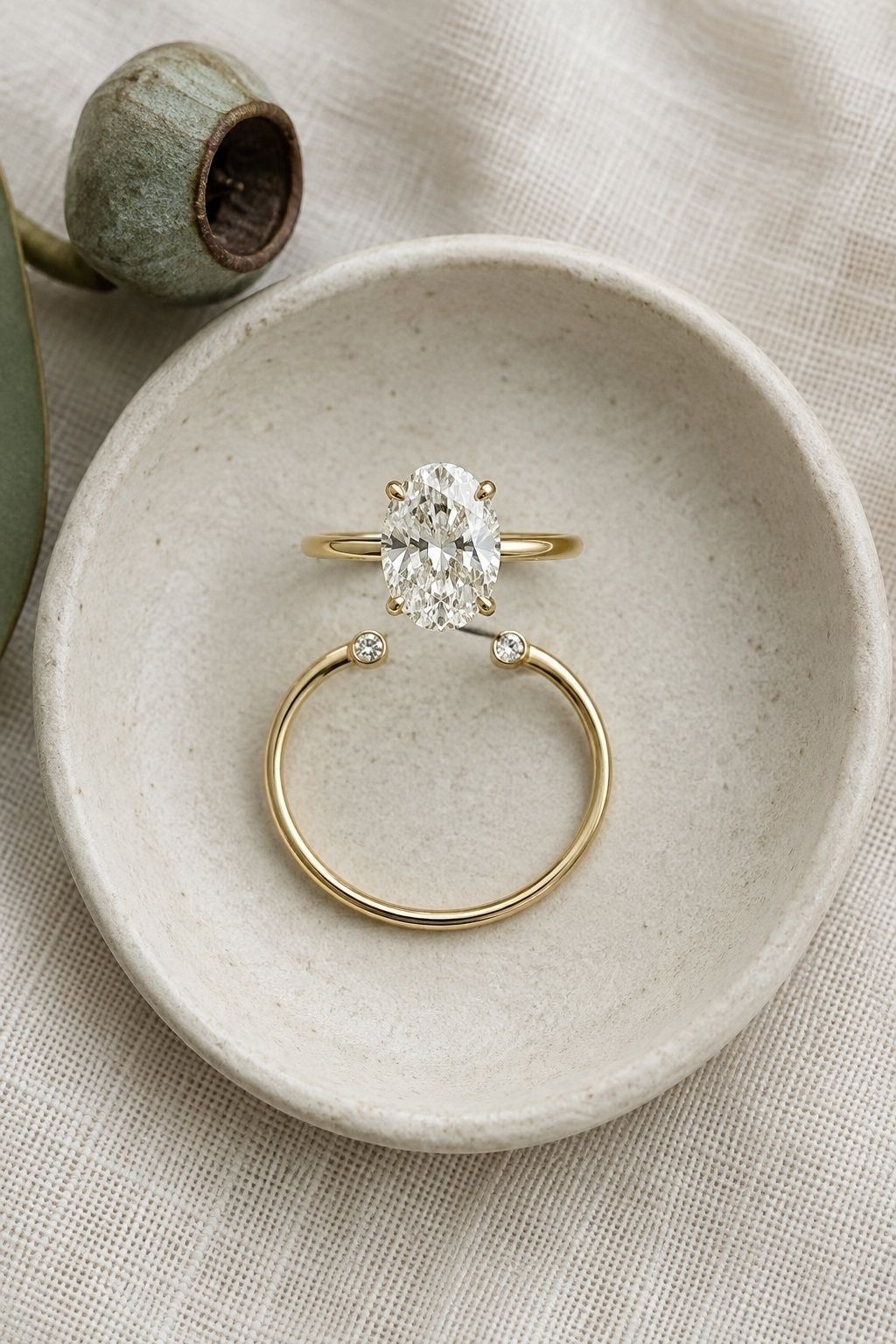 Oval engagement ring paired with an open gold wedding band with two diamond tips