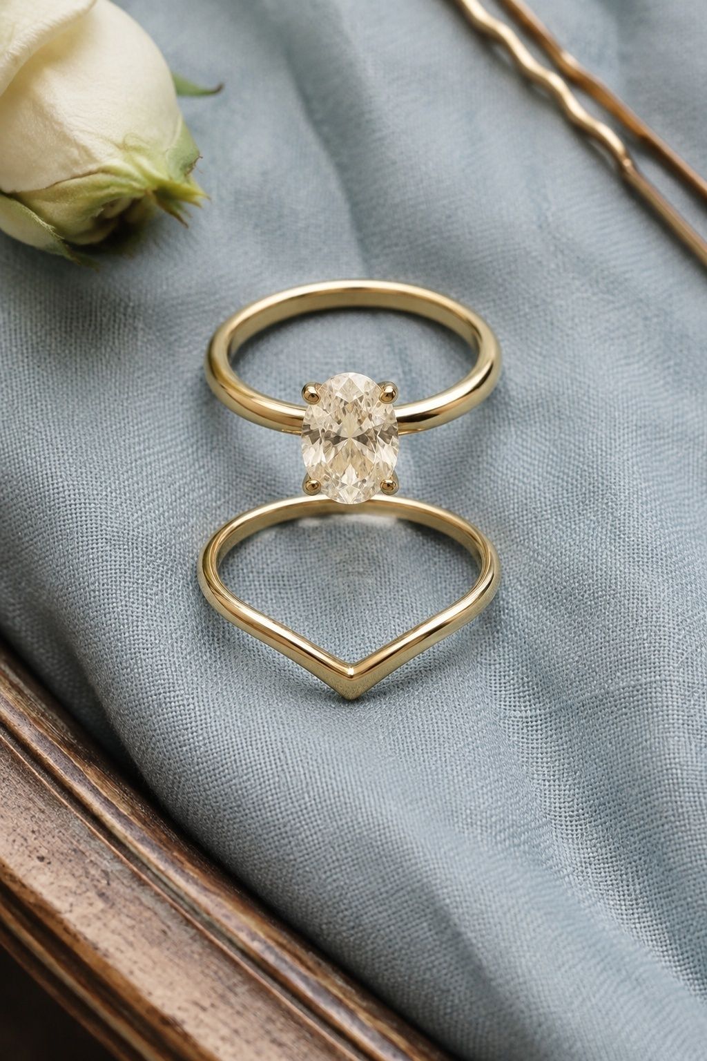 Oval engagement ring framed by a shallow V-shaped gold wedding band