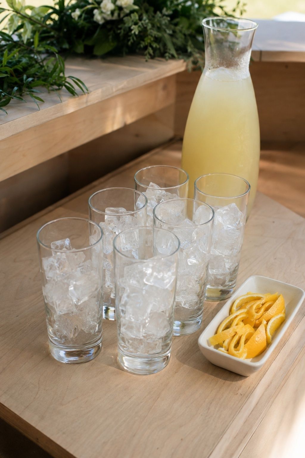 Fast-pour wedding cocktail station with iced highballs, citrus carafe, and lemon twists