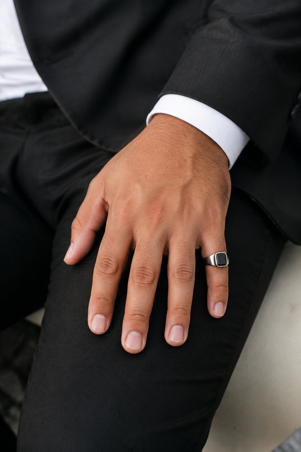 Silver signet pinky ring worn with a black suit