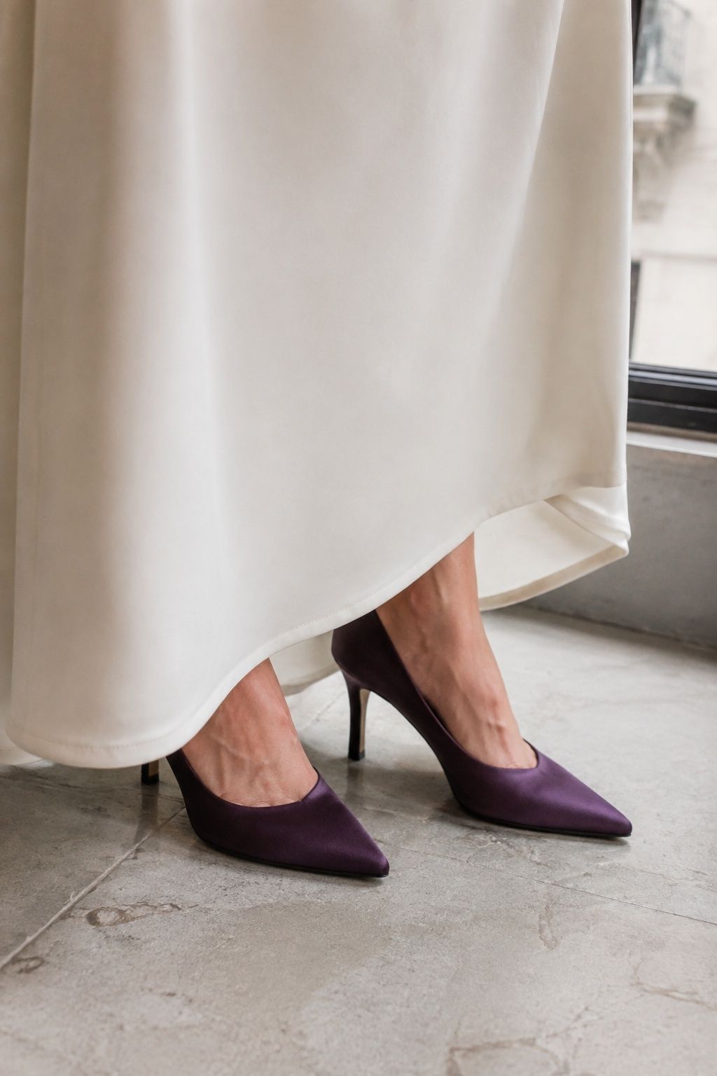 Plum satin pumps peeking from under a white wedding gown